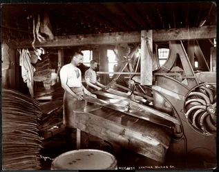 Interiör av två män som arbetar med läder och tung utrustning på New York Leather Belting Co. i New York, 1905 (silvergelatintryck).